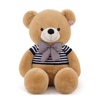 A large brown teddy bear with a white nose and eyes wearing a blue and white striped shirt and a checkered bow tie sitting on a white background